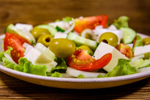 Piatto in ceramica con insalata greca su tavola di legno