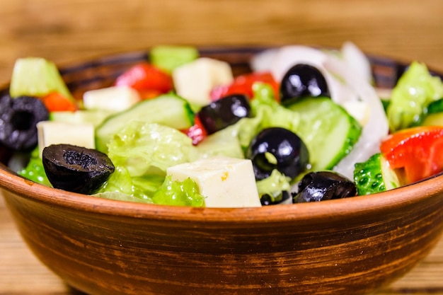 Piatto in ceramica con insalata greca su tavola di legno