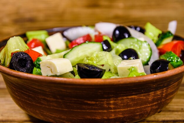 Piatto in ceramica con insalata greca su tavola di legno