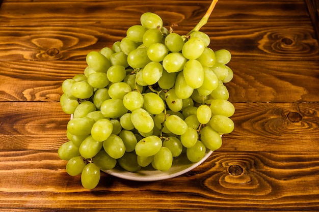 Piatto in ceramica con uva verde su tavola di legno