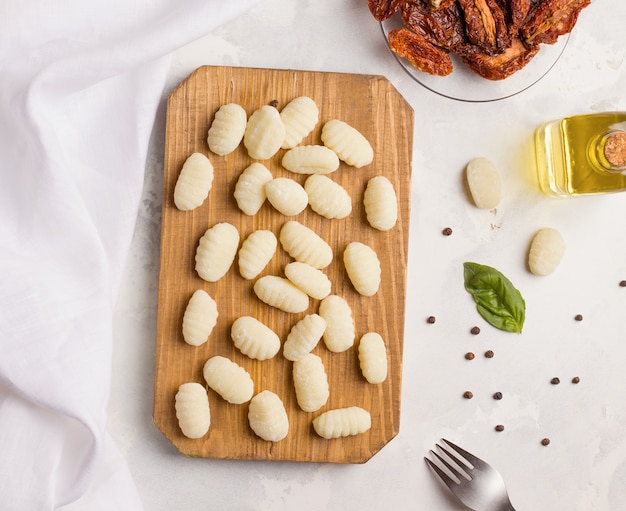 Piatto italiano di gnocchi di patate su una tavola di legno accanto a spezie ed erbe aromatiche. Vista dall'alto