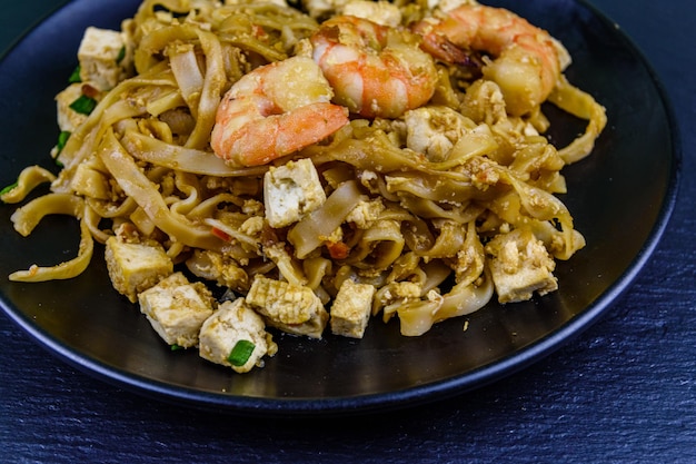 Piatto nero con pad thai su tavola di ardesia