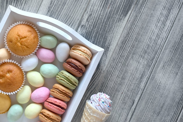 Piatto pasquale con macarons, muffin e uova di marzapane su legno grigio