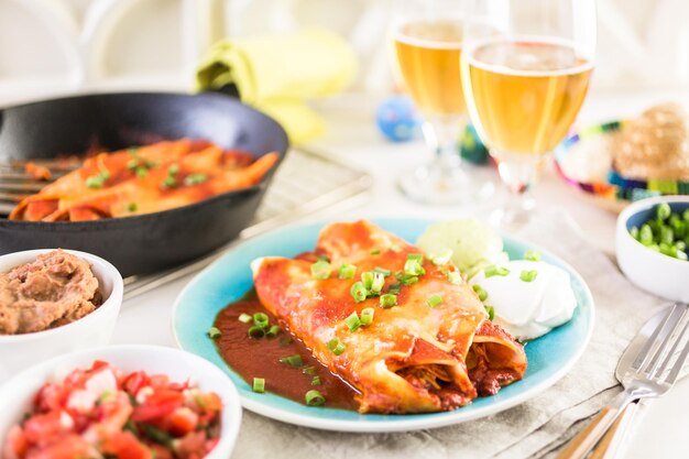 Piatto piano con enchiladas di pollo guarnite con cipolle verdi e panna acida.