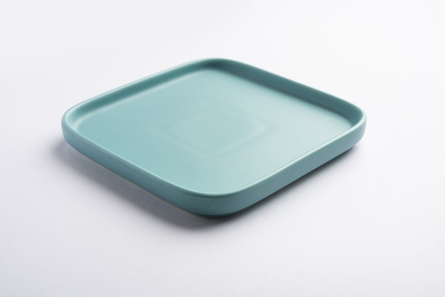 Piatto quadrato in ceramica verde chiaro o blu vuoto isolato su sfondo bianco