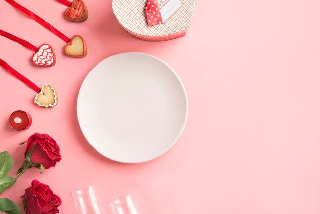 Piatto rosa con biscotti e rose per San Valentino su sfondo rosa.