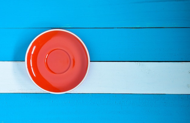 Piatto rosso su fondo di legno blu