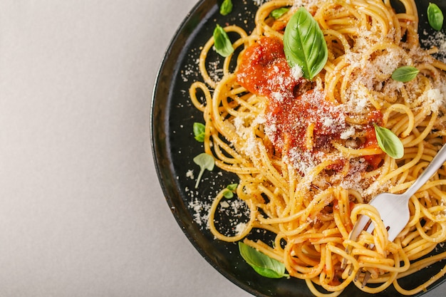 Piatto scuro con spaghetti italiani su grigio