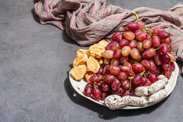 Piatto snack con uva da formaggio e salsicce secche Antipasto di salumi fondo in cemento di pietra