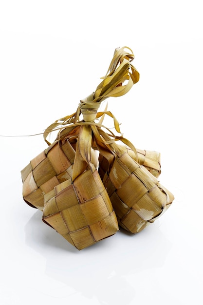 Piatto speciale di gnocchi di riso Ketupat servito a Eid Mubarakisolato su sfondo bianco Ketupat è riso cotto con foglie di cocco giovani involucro Celebrazione musulmana di Eid al Fitr