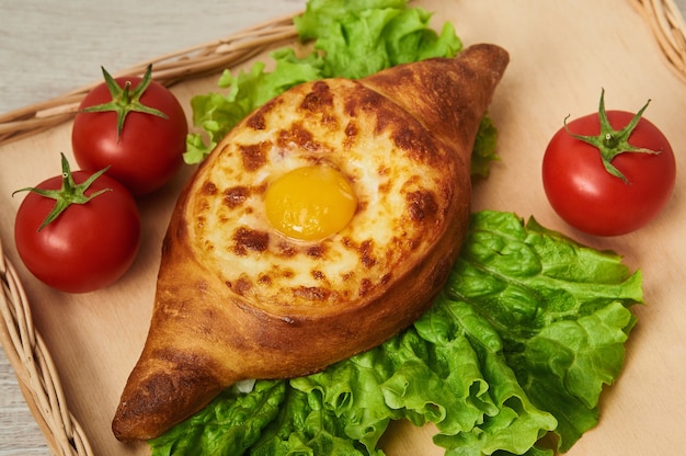 Piatto tradizionale georgiano di pane fragrante ripieno di formaggio su un tavolo di legno. Adjaran aperto khachapuri.