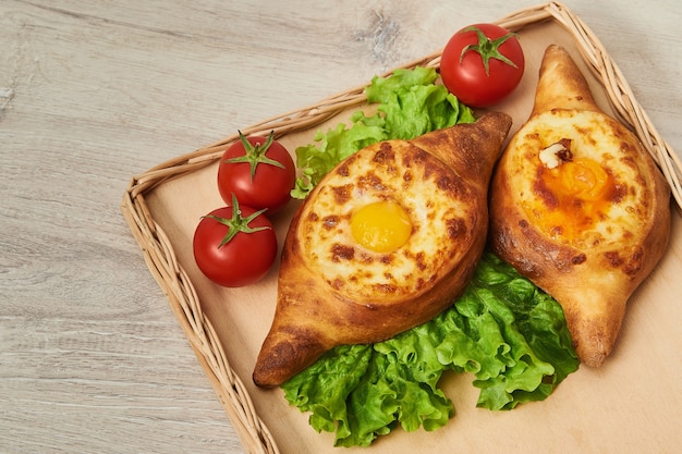 Piatto tradizionale georgiano di pane fragrante ripieno di formaggio su un tavolo di legno. Adjaran aperto khachapuri.