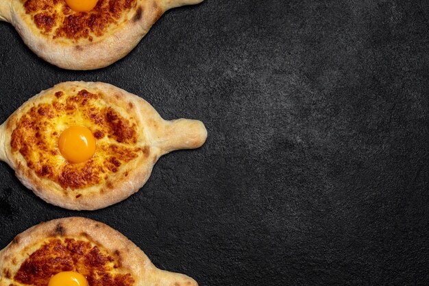 Piatto tradizionale georgiano Khachapuri adjarian su sfondo scuro decorato pasticceria fresca calda