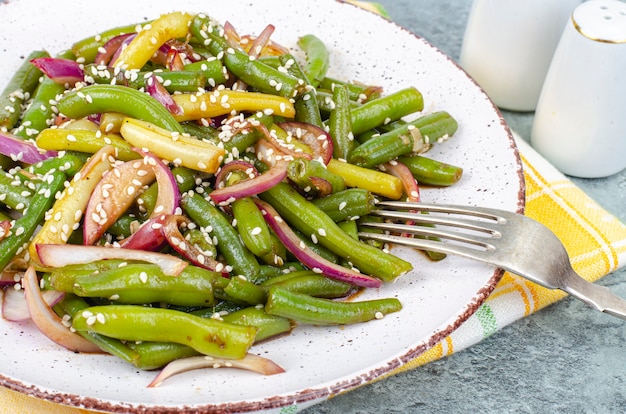 Piatto vegetariano a base di fagiolini con cipolle rosse sottaceto e semi di sesamo. Foto dello studio.