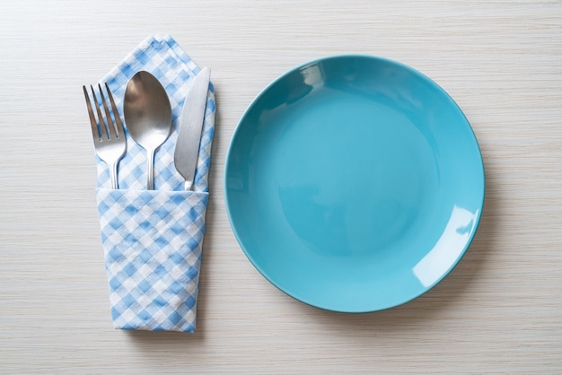 piatto vuoto o piatto con coltello, forchetta e cucchiaio su piastrelle di legno