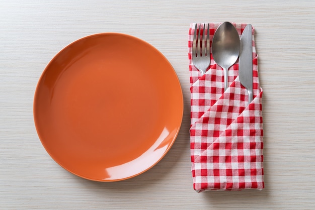piatto vuoto o piatto con coltello, forchetta e cucchiaio su sfondo di piastrelle di legno