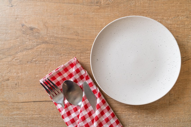 piatto vuoto o piatto con coltello, forchetta e cucchiaio sulla tavola di legno