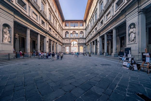 Piazzale degli Uffizi e famosa galleria d'arte nel palazzo medievale con persone che camminano Firenze Italia