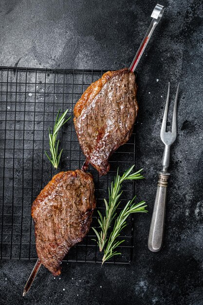 Picanha tradizionale brasiliana barbecue bistecca di carne di manzo alla griglia Sfondo nero Vista dall'alto