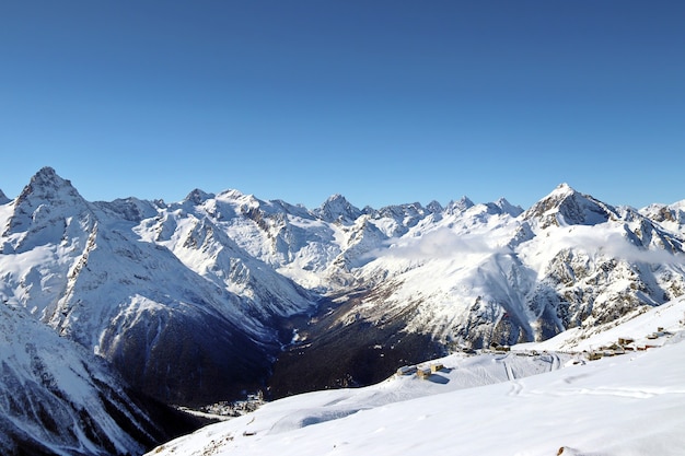 Picchi delle montagne innevate nel cielo blu delle nuvole Caucaso