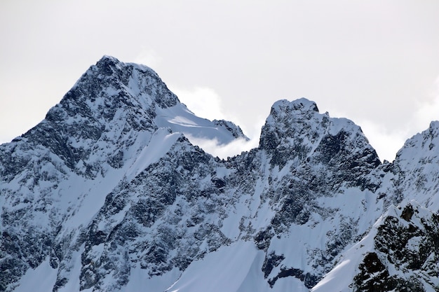 Picchi delle montagne innevate nel cielo blu delle nuvole Caucaso