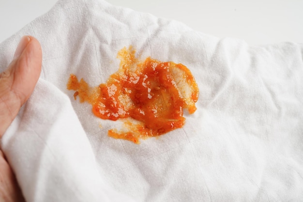 Picchia di salsa di pomodoro sporca o ketchup sul panno da lavare con detergente per la lavanderia concetto di pulizia domestica