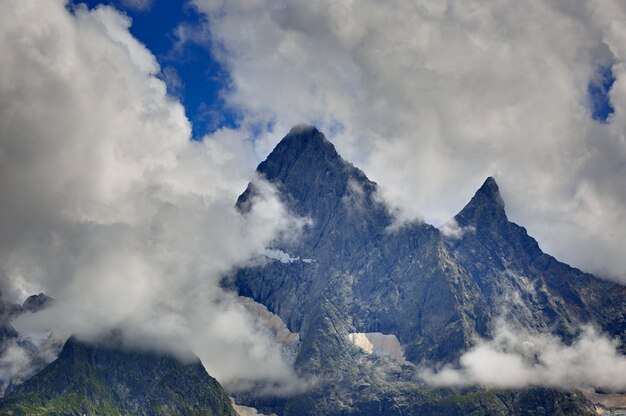 Picco della montagna con i ghiacciai sullo sfondo delle nuvole e del cielo Cresta caucasica Russia