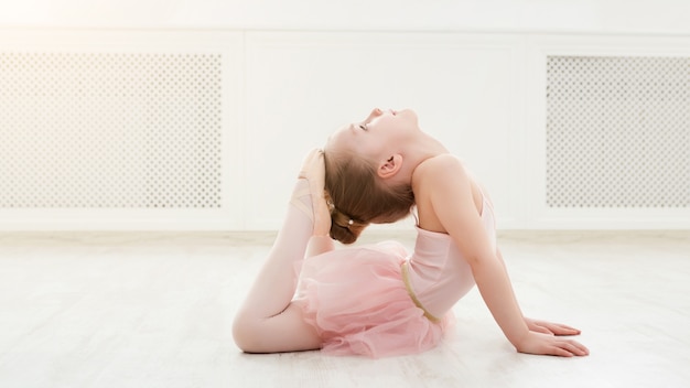 Piccola ballerina in spaccato sul pavimento, copia dello spazio. Bambina sorridente che sogna di diventare ballerina professionista, scuola di danza classica