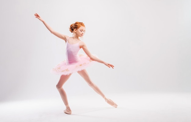 Piccola ballerina in uno studente dell'accademia tutu rosa in posa su uno sfondo bianco