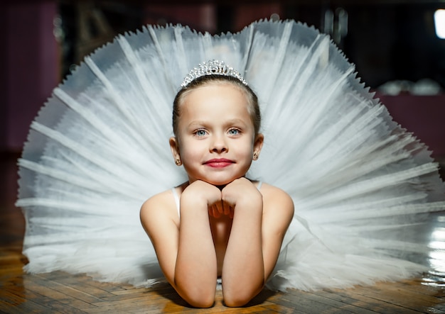 Piccola ballerina sorridente in un tutu bianco che risiede nello studio di ballo