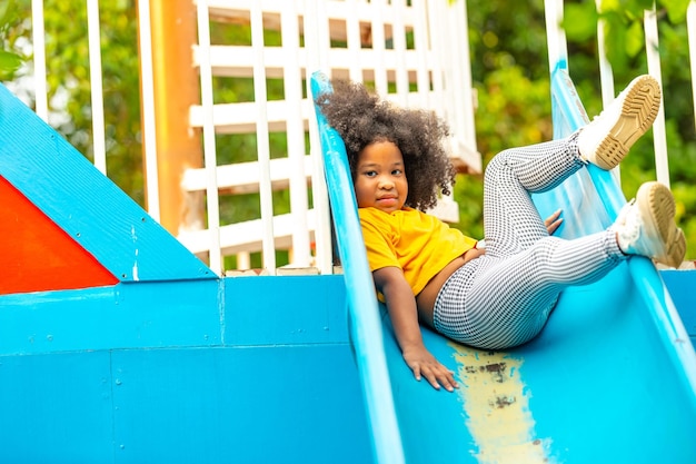 Piccola bambina africana felice che scivola e gioca nel parco all'aperto durante le vacanze estive I bambini dell'asilo si divertono e si divertono con le attività all'aria aperta imparando ed esercitando a scuola