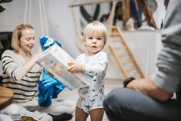 Piccola bambina bionda caucasica carina che spacca il regalo di Natale o di compleanno un bambino adorabile