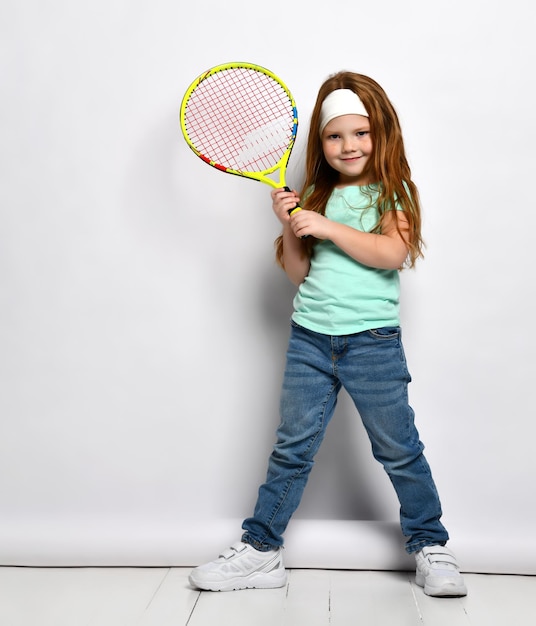 Piccola bambina dai capelli rossi grande tennista ritratto a figura intera