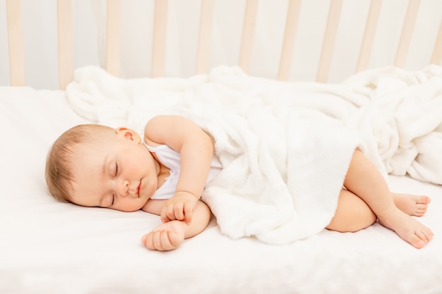 Piccola bambina di 6 mesi che dorme in un letto bianco, sonno sano del bambino