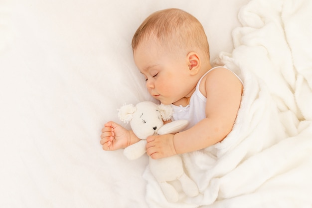 Piccola bambina di 6 mesi che dorme in un letto bianco, sonno sano del bambino