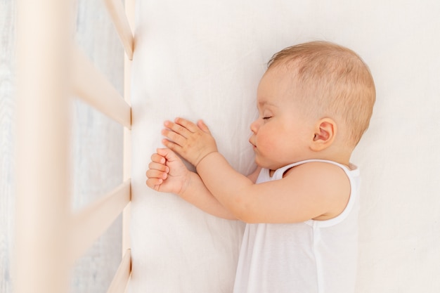 Piccola bambina di 6 mesi che dorme in un letto bianco