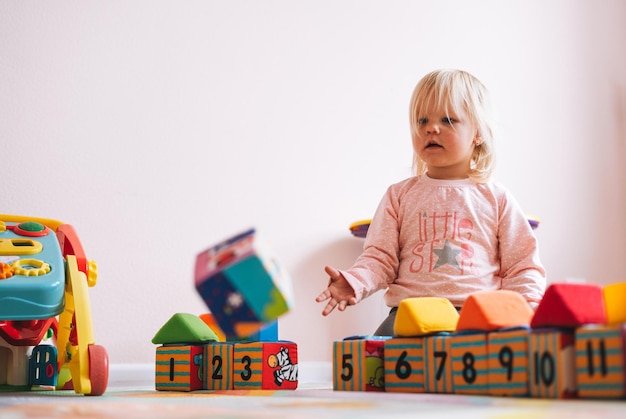 Piccola bambina in rosa che gioca con i blocchi con i numeri nella stanza dei bambini a casa