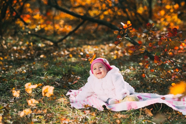 Piccola bambina seduta su una coperta nella foresta autunnale