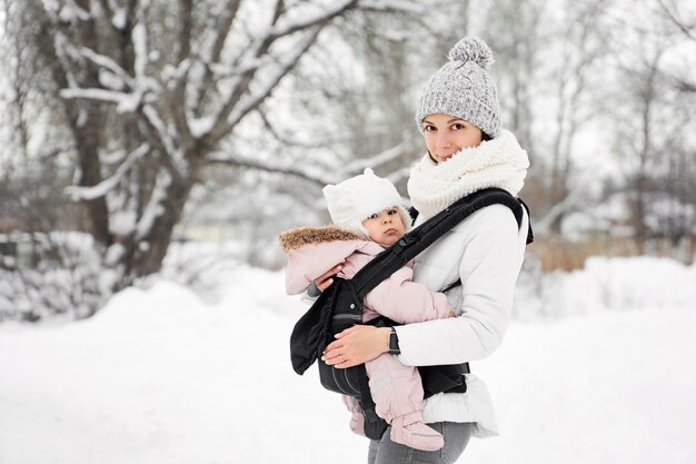 Piccola bambina sua madre che cammina fuori in inverno Madre holding baby babywearing
