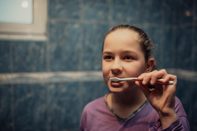 Piccola bella ragazza che pulisce i denti concetto sano