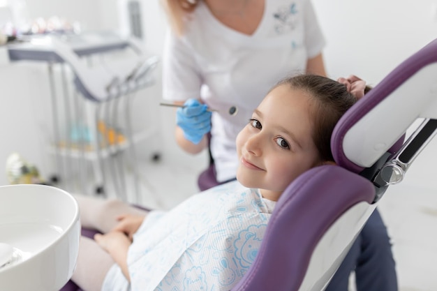 Piccola bella ragazza dal dentista guardando la telecamera e sorridente