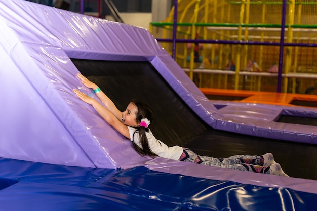 Piccola bella ragazza sorridente sdraiata sul trampolino.