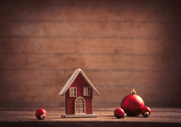 Piccola casa del giocattolo e bagattelle di Natale su fondo di legno