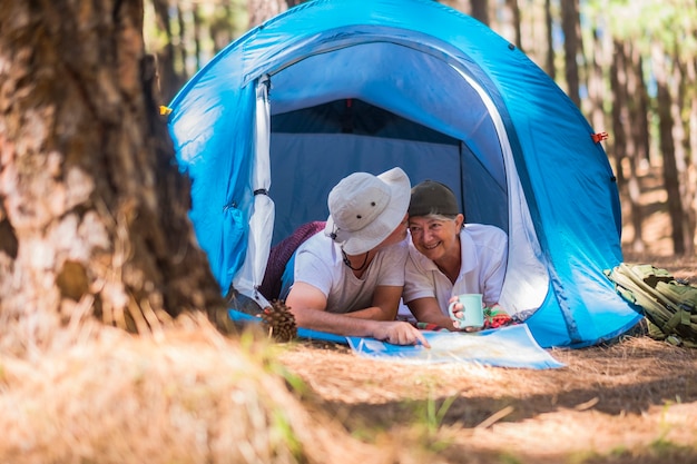 Piccola casa nel bosco per una coppia di pensionati adulti allegri e allegri. sorridere guardando la mappa per il prossimo passo della loro vita alternativa e viaggiare insieme per sempre