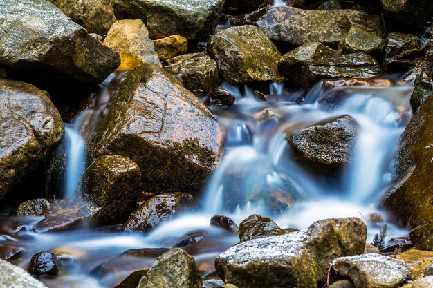 Piccola cascata con acqua schiumosa blu su pietre bagnate