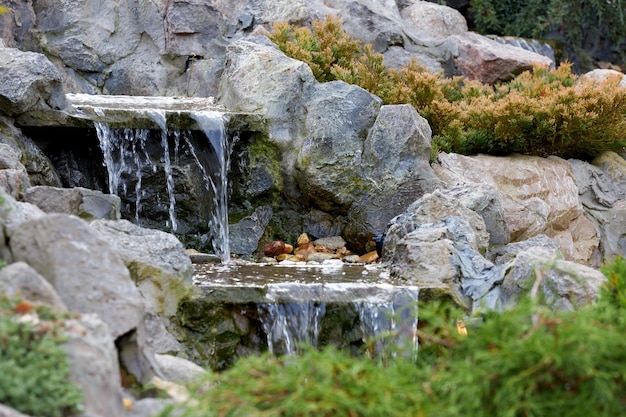 Piccola cascata di fiume decorativa. L'acqua scorre su rocce e pietre.