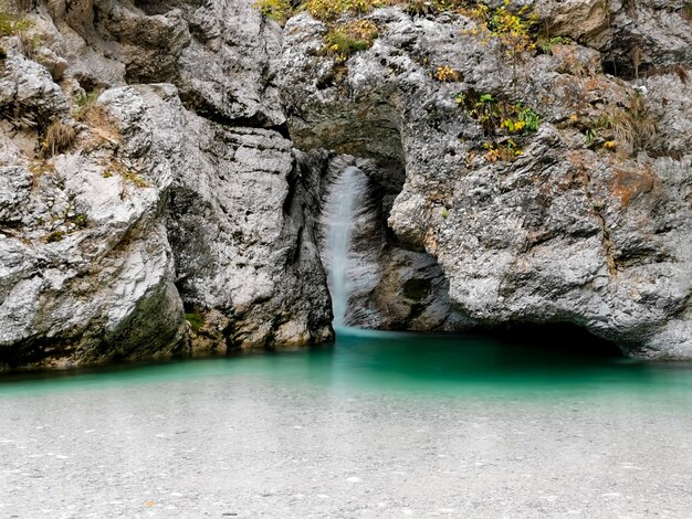 Piccola cascata idilliaca che crea una piscina naturale con acqua trasparente turchese sotto una parete rocciosa