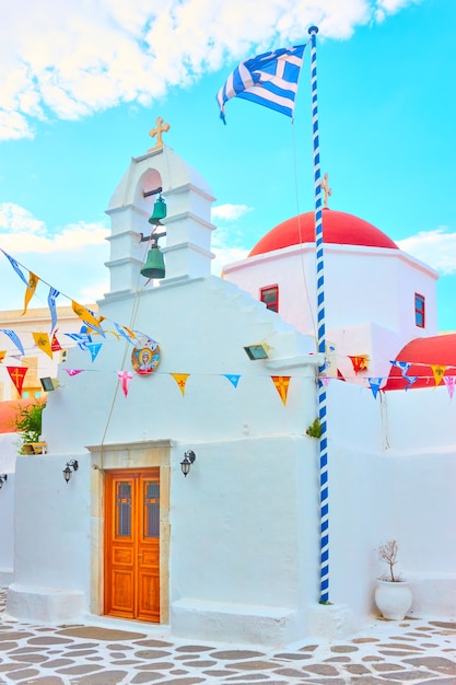 Piccola chiesa ortodossa bianca con bandiera greca nella città di Mykonos, Grecia