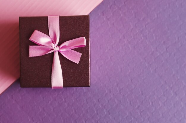 Piccola confezione regalo decorativa con nastro rosa su viola e rosa