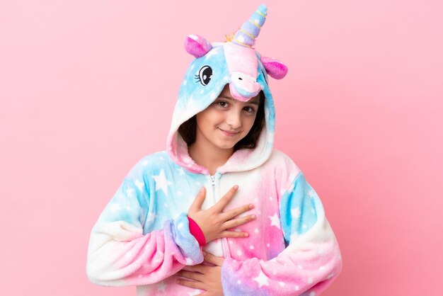 Piccola donna caucasica che indossa un pigiama unicorno isolato su sfondo rosa che sorride molto